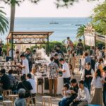 湘南海街珈琲祭2025開催を前にした、海沿いのコーヒーフェスティバルの賑わいを表現。人々が楽しむ様子やコーヒースタンドが描かれたシーン。
